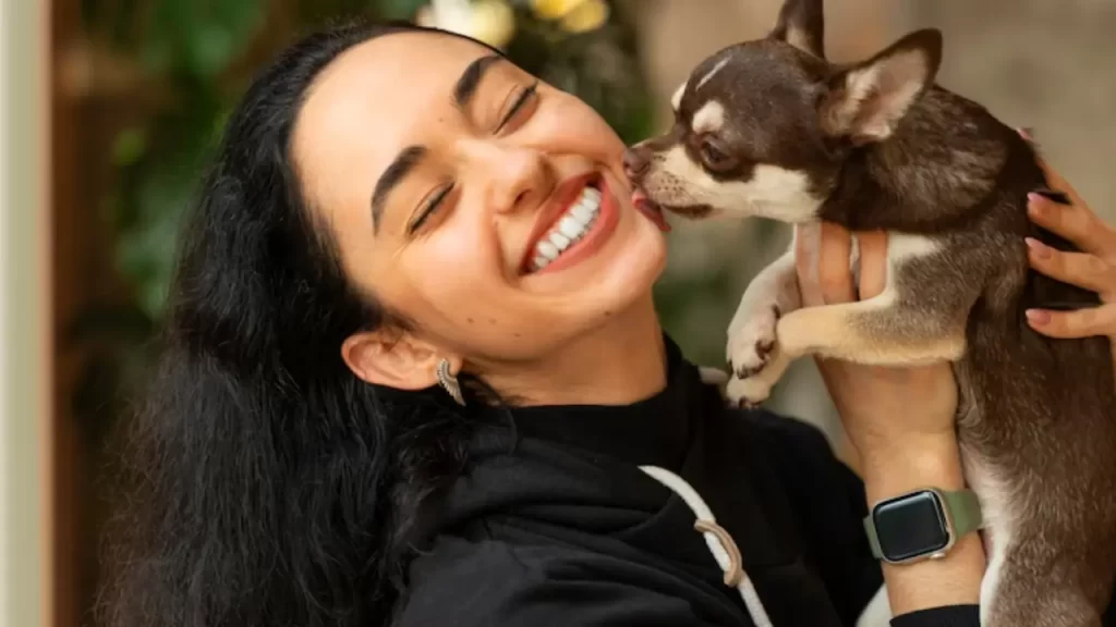 Mulher sorrindo enquanto abraça seu cachorro carinhosamente
